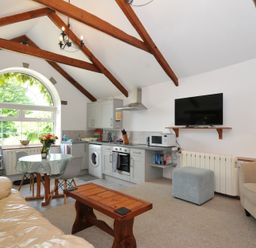 A living room kitchen with appliances and furniture at Trevenning Chapel Near Port Isaac