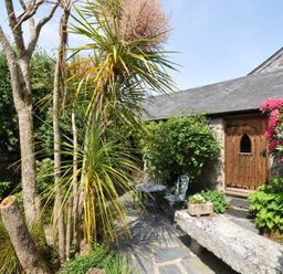 A garden with plants and a stone bench at Trevenning Chapel near Port Isaac