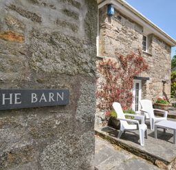 An outdoor seating area with chairs and a table at Trevenning Barn near Port Isaac