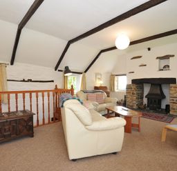 A living room with a fireplace and sofa at Trevenning Barn near Port Isaac