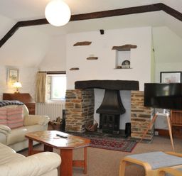 A living room with a fireplace and sofa at Trevenning Barn near Port Isaac