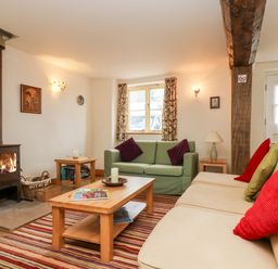 A living room with a wood-burning stove two sofas a coffee table and striped rug at Apple Cottage in Colebrooke near Crediton