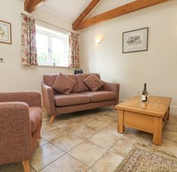 A living room with sofa armchair wooden coffee table and tiled floor at Byre in Lostwithiel