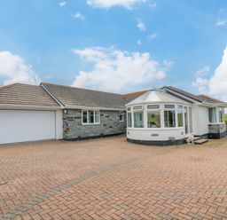 A single story house with a large driveway garage and conservatory at Bethany Bay View in Holywell Bay