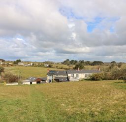 A rural landscape with a farmhouse and outbuildings surrounded by fields and trees at Mynheer Farm Barn Nr Portreath