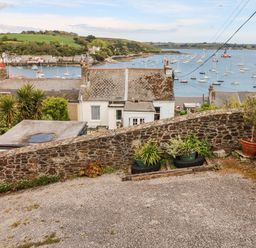 A sloped outdoor area with stone walls potted plants and a view of houses and a harbor with boats at Seabien in Falmouth