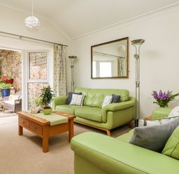 A living room with green sofas wooden coffee table and lamps by a window at Seabien in Falmouth
