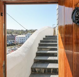 Stone steps leading up outside through a wooden door with view of boats and buildings