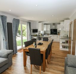 A living room with a dining table and kitchen area at Glebe House in Bigbury