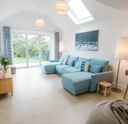 A living room with a blue sofa and glass door at Lanesend in St Agnes