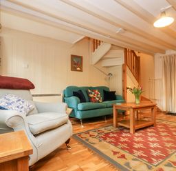 A living room with two sofas a wooden coffee table and a patterned rug at Gurnard's Cottage in St Ives