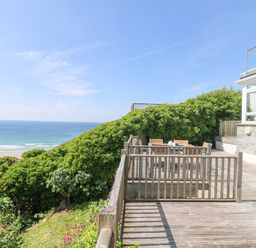 A wooden deck with outdoor furniture and ocean view at St Ives View in Porthtowan
