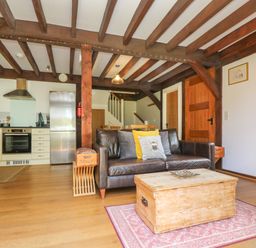 An open plan living area with a leather sofa and wooden coffee table near a kitchen and dining table at Oaklands Near Boscastle