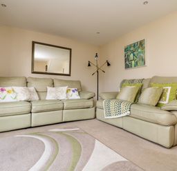 A living room with two sofas cushions a rug a floor lamp and a mirror on the wall at Riverview in Lostwithiel