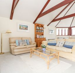 A living room with two sofas a glass coffee table a wooden bookshelf and large windows at Lookout in Falmouth