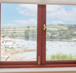 A view of a harbor with boats and houses through a wooden window at Lookout in Falmouth