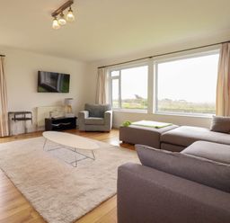 A living room with a sofa and armchair at Seaport Lodge in Mawgan Porth