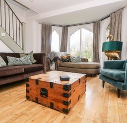 A living room with a brown sofa a gray chaise lounge a green armchair and a wooden chest used as a coffee table at Lost Barn in Watergate Bay