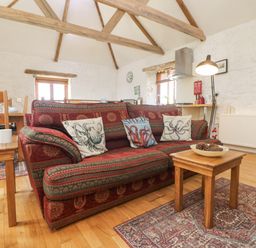A living room with a patterned sofa and wooden coffee table with pine cones at Courtyard Nancegollan nr Porthleven