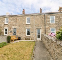 A stone house with a front garden bench flowers and a pathway at Boslow in St Just