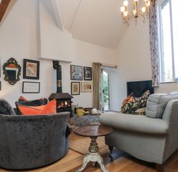 A sitting room with sofas a wood burning stove and framed pictures on the wall at Hideaway in Watergate Bay