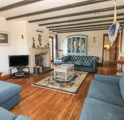 A living room with blue sofas a fireplace TV a coffee table and a blue cabinet at Mengarth in Cadgwith