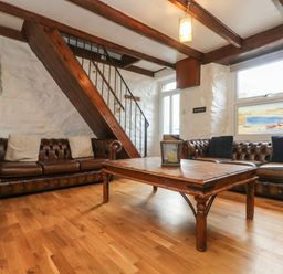 A living room with two brown leather sofas a wooden coffee table and wooden staircase at Trevean in Portreath