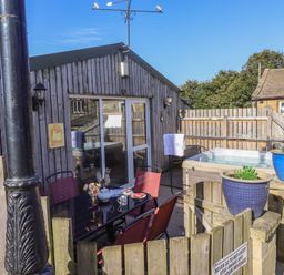 An outdoor patio area with a table and chairs a hot tub and potted plants at The Old Hen Shed in Hainworth near Haworth