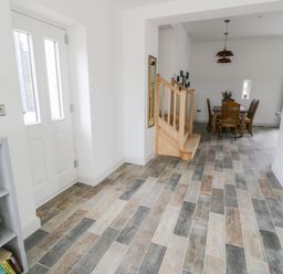 A hallway with a staircase next to a dining area with a table and chairs at Storws in Pentraeth
