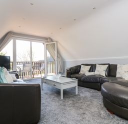 A living room with black leather sofas white coffee table and sliding glass doors leading to a balcony at Valley Lodge 58 in Callington