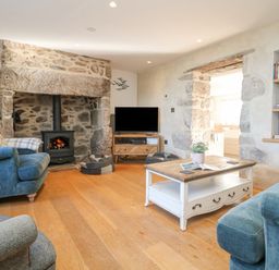 A living room with a stone fireplace wooden floor sofas a coffee table and a television at Bal View in St Just