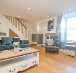 A living room with blue sofas a wooden coffee table and a window at Bal View in St Just