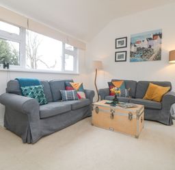 A living room with two gray sofas a wooden chest coffee table two floor lamps and artwork on the wall at Mackerel Sky in Marazion