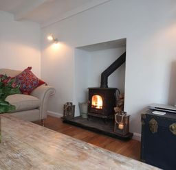A living room with a fireplace and a television at Trelan in Mevagissey