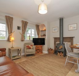 A living room with a fireplace and dining table at Stocks Barn in Looe