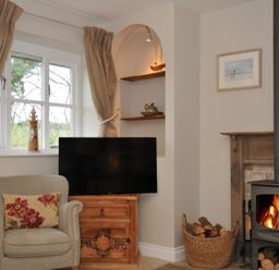 A living room with a tv and a wood burner at Stocks Barn Looe