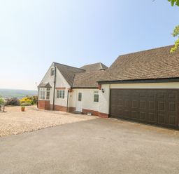 An exterior view of a house with a double garage door and gravel driveway at Charlesworth in Braunton