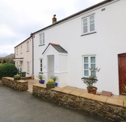 A white terrace house with a wooden front door and small porch with potted plants outside at Speedwell in Charlestown