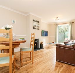A dining and living room with wooden chairs and a table beside brown leather sofas at Speedwell Charlestown