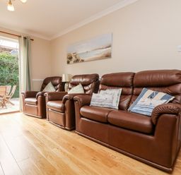 A living room with brown leather sofas and cushions next to a door opening to an outdoor patio at Speedwell in Charlestown