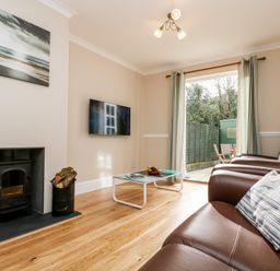 A living room with leather sofas a glass coffee table wall mounted television and a wood burning stove at Speedwell in Charlestown