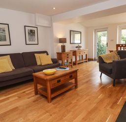 A living room with a sofa armchair wooden tables and framed pictures on the wall at Anneth Lowen in Angarrack near Hayle
