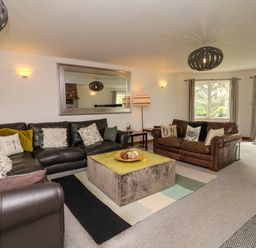 A living room with two leather sofas cushions a large mirror and a central coffee table at Nairn in Braunton