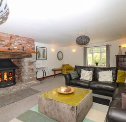A living room with a fireplace black leather sofas and a large square coffee table at Nairn in Braunton
