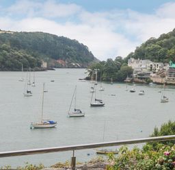 A view of boats on the water with hills and buildings in the background at Bight Boathouse in Dartmouth