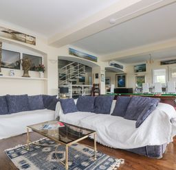 A room with two sofas with cushions a glass coffee table and a pool table in the background at Bight Boathouse Dartmouth