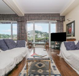 A living room with two sofas and a glass coffee table facing a television and large sliding glass doors at Bight Boathouse in Dartmouth