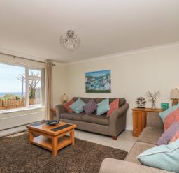 A living room with sofas and cushions a wooden coffee table and a side cabinet with lamps at Hagar Vor in Marazion