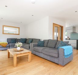 A living room with gray sofas and a wooden coffee table with flowers at Lake View in Kingsand and Cawsand