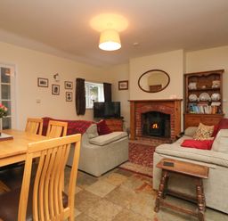 A living room with sofas a wooden dining table a fireplace and a television at Goslings in Bradford Holsworthy